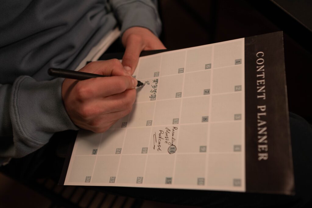 Close-up of hands writing in a content planner for organizational purposes.