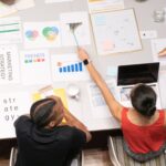 Colleagues collaborating on marketing strategy with documents and graphs in a modern office setting.